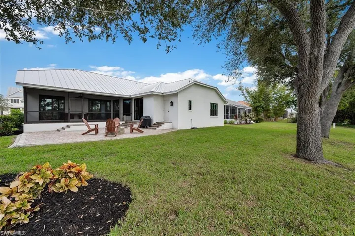 Back of house with a patio, a sunroom, stucco siding, a lawn, and metal roof
