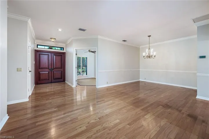 Foyer entrance featuring a chandelier, crown molding, light wood-type flooring, and baseboards