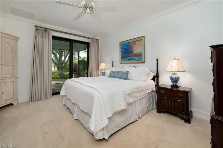 Bedroom with light colored carpet, baseboards, ornamental molding, and access to outside