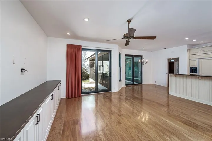 Unfurnished living room featuring recessed lighting, ceiling fan with notable chandelier, light wood-type flooring, and baseboards