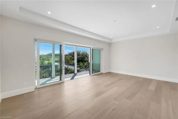 Empty room featuring a raised ceiling, light wood-style floors, and recessed lighting
