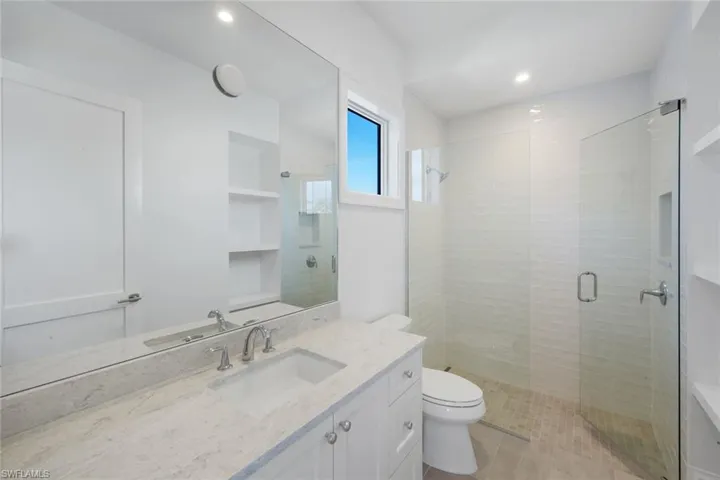 Bathroom with a shower stall, vanity, and recessed lighting