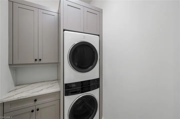 Laundry area with stacked washer and clothes dryer and cabinet space