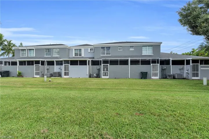 Back of property with a lawn, a sunroom, and central air condition unit