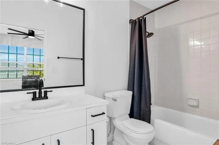 Full bathroom with ceiling fan, toilet, shower / tub combo with curtain, and vanity