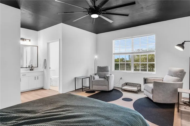 Bedroom featuring ceiling fan, light wood-type flooring, sink, and ensuite bathroom
