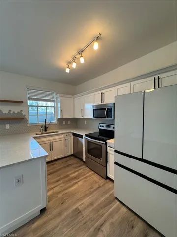 Kitchen featuring stove, white cabinets, sink, hardwood / wood-style flooring, and dishwasher