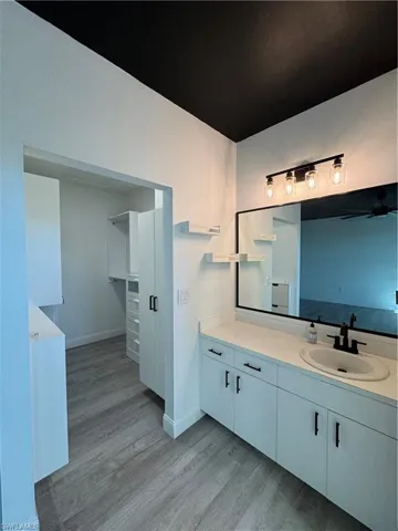 Bathroom with vanity, ceiling fan, and wood-type flooring