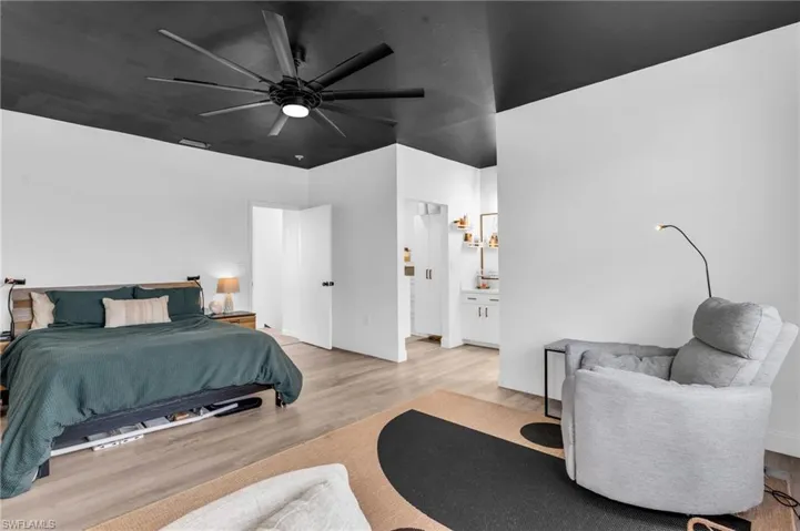 Bedroom with ceiling fan, light wood-type flooring, and ensuite bathroom