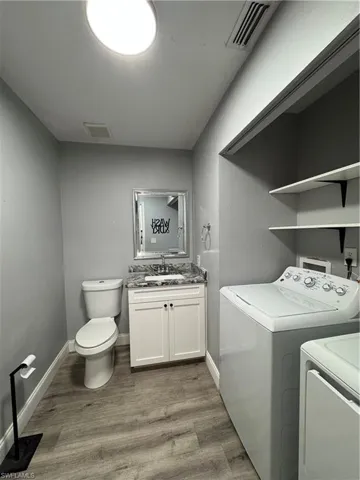 Laundry area with independent washer and dryer, light hardwood / wood-style floors, and sink