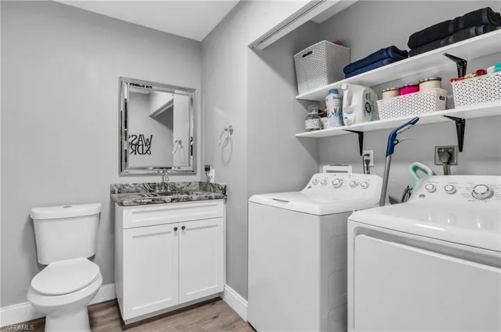 Laundry room with washing machine and clothes dryer, sink, and wood-type flooring