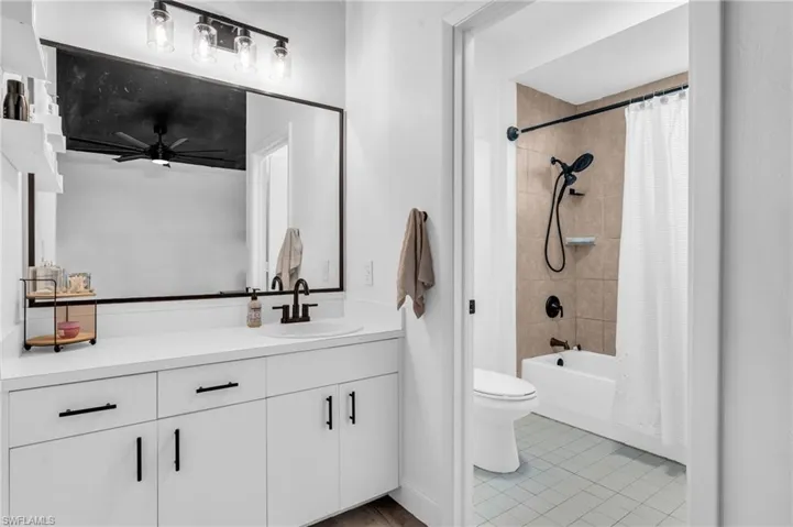 Full bathroom featuring tile patterned flooring, shower / bath combo, toilet, ceiling fan, and vanity