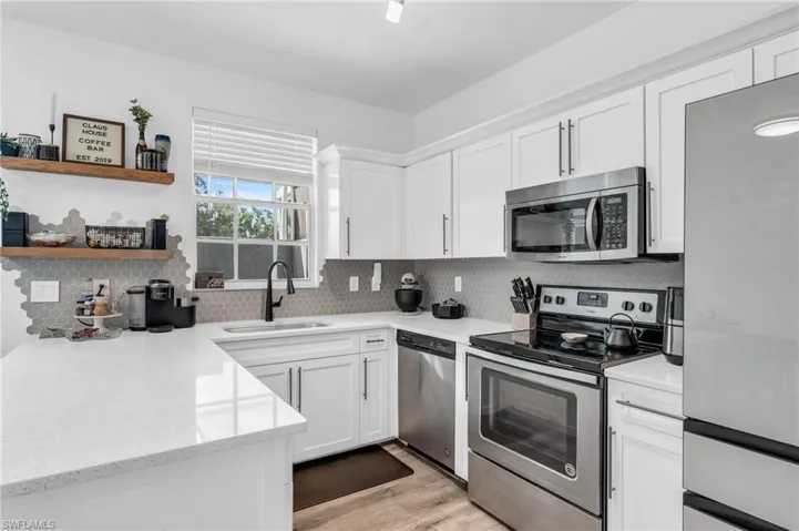 Kitchen featuring appliances with stainless steel finishes, light hardwood / wood-style floors, white cabinetry, sink, and decorative backsplash
