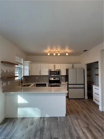 Kitchen with tasteful backsplash, sink, range, white cabinetry, and fridge