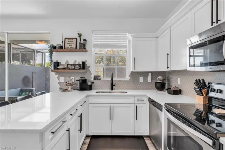 Kitchen with appliances with stainless steel finishes, white cabinetry, plenty of natural light, and sink