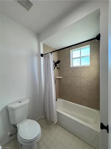Bathroom with tile patterned flooring, shower / bath combo, and toilet