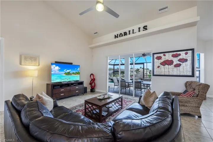 Tiled living room featuring ceiling fan and high vaulted ceiling