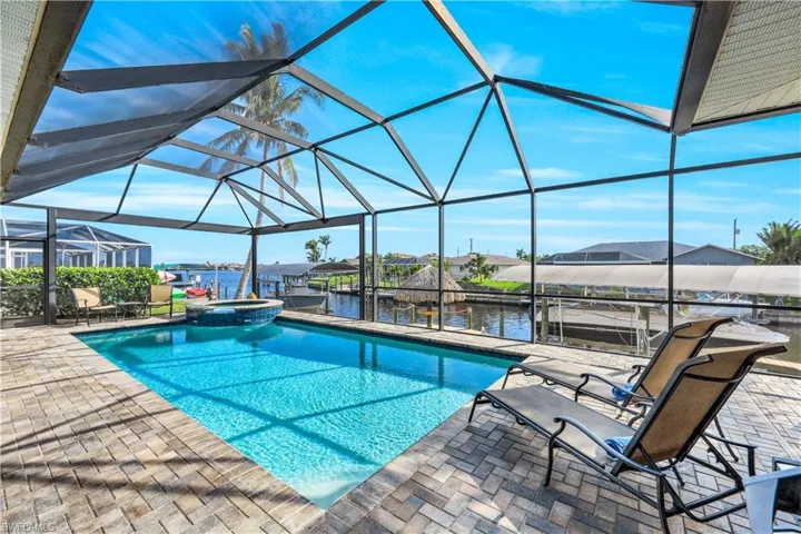 View of pool featuring  enclosure, a water view, a patio, and a spa