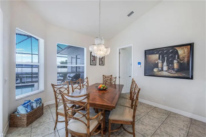 Dining room featuring light tile patterned floors, lofted ceiling, and a chandelier