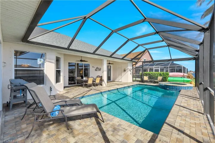 View of swimming pool with  enclosure, ceiling fan, and a patio area