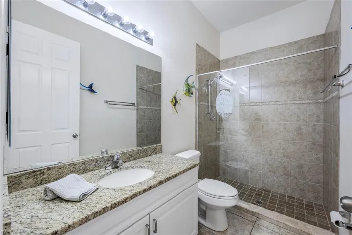 Bathroom with tile patterned floors, tiled shower, vanity, and toilet