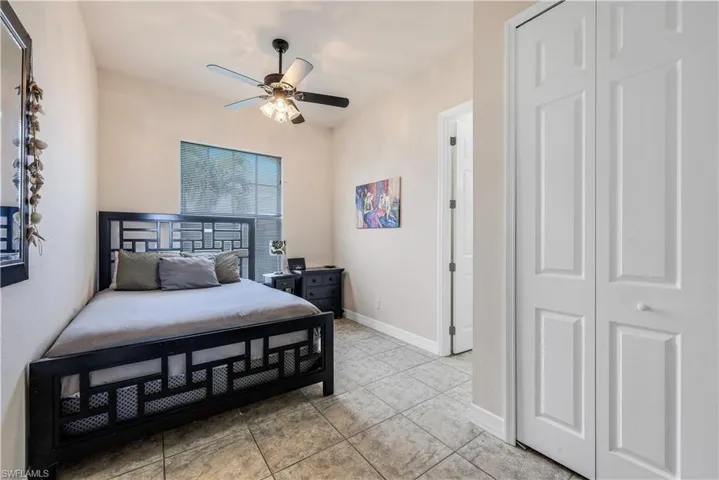 Tiled bedroom with ceiling fan and a closet