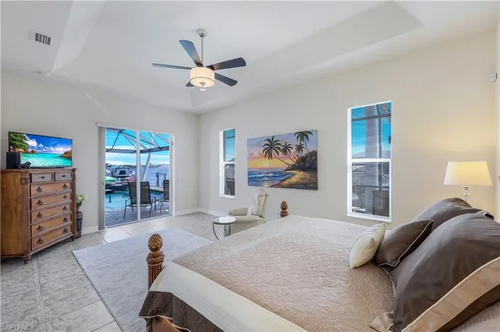 Bedroom featuring access to outside, light tile patterned flooring, a raised ceiling, and ceiling fan