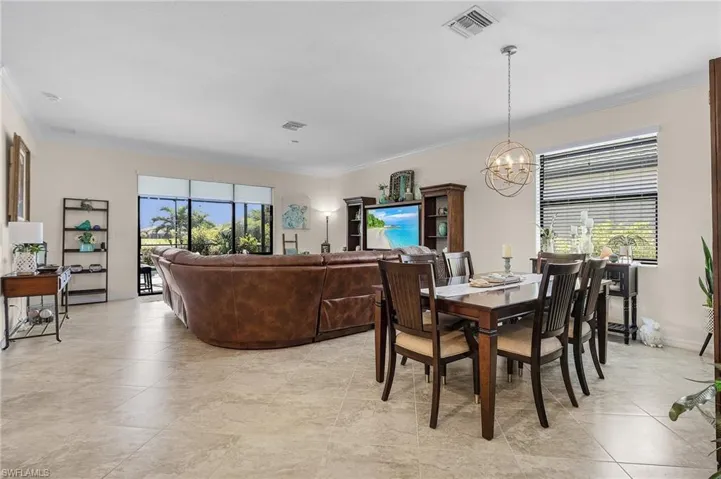 Tiled dining room with a wealth of natural light, a chandelier, and crown molding