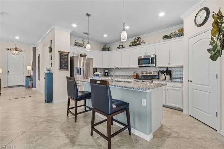 Kitchen featuring stainless steel appliances, a kitchen island with sink, light stone counters, sink, and decorative backsplash