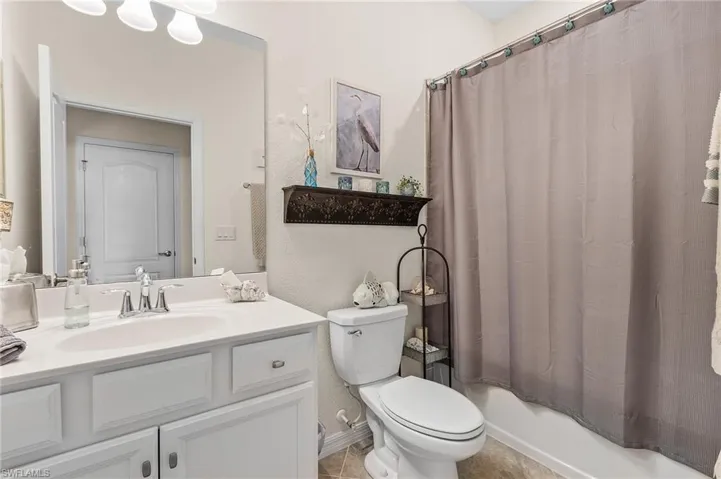 Full bathroom with tile patterned floors, shower / bath combination with curtain, vanity, and toilet