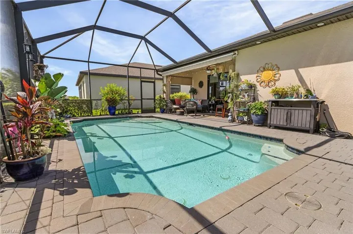 View of swimming pool with glass enclosure and a patio area