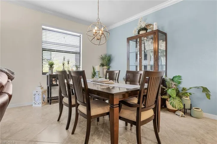 Dining room featuring ornamental molding, light tile patterned floors, and an inviting chandelier