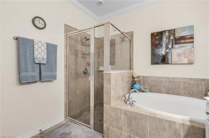 Bathroom featuring ornamental molding and plus walk in shower