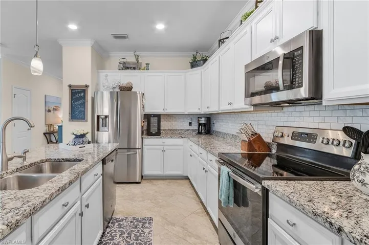 Kitchen with appliances with stainless steel finishes, crown molding, sink, and light tile patterned floors