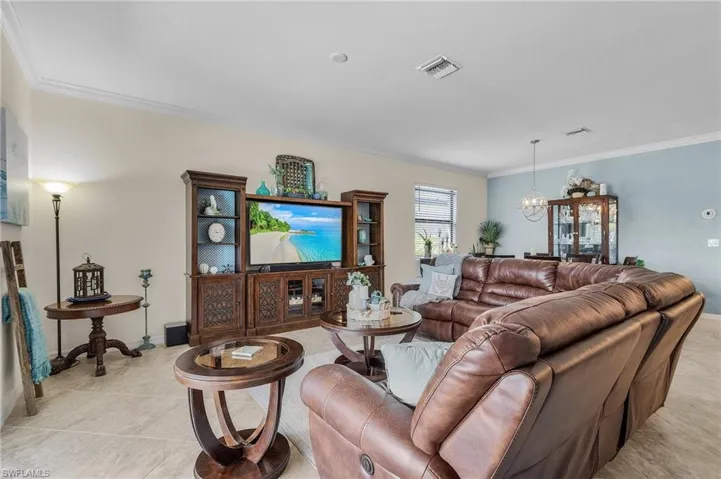 Tiled living room with crown molding and a chandelier