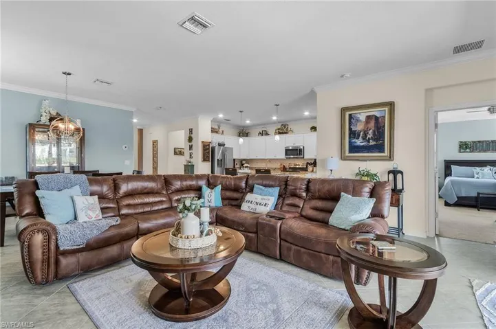 Tiled living room featuring ornamental molding and an inviting chandelier