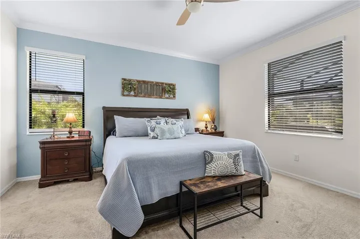 Carpeted bedroom featuring ceiling fan and crown molding