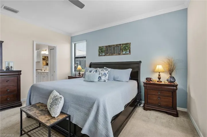 Bedroom featuring ceiling fan, ensuite bathroom, light colored carpet, and crown molding