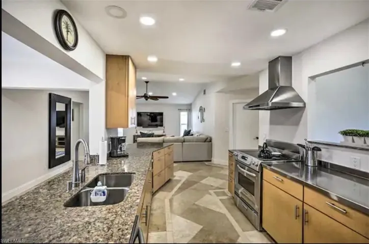 Kitchen featuring stainless steel electric stove, ventilation hood, recessed lighting, open floor plan, and ceiling fan
