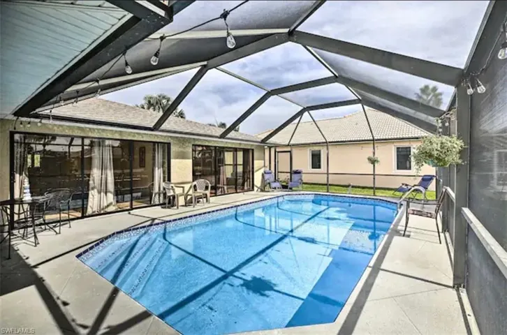 Swimming pool featuring glass enclosure, a patio area, and a sunroom