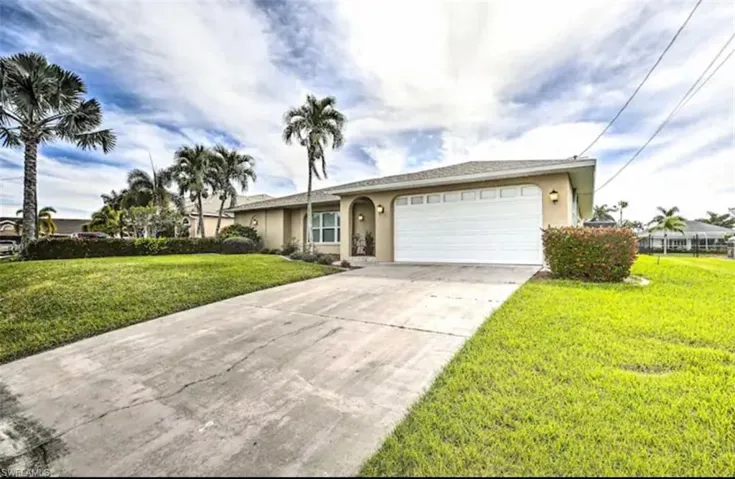Single story home with stucco siding, a front lawn, a garage, and driveway