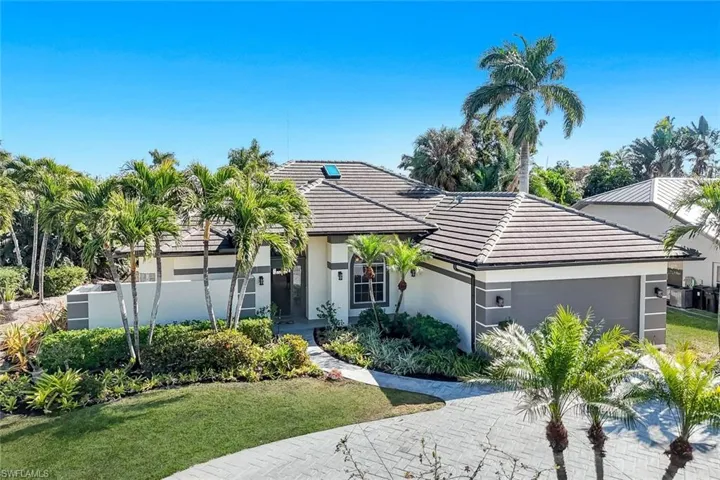 View of front of house featuring an attached garage, a front lawn, stucco siding, driveway, and a tile roof