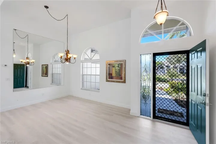 Entryway with light wood finished floors, a high ceiling, and a chandelier