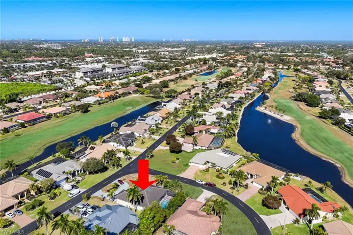 Aerial view of property's location featuring a large body of water, nearby suburban area, and a golf club