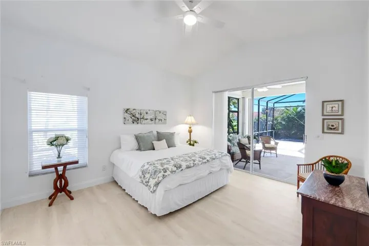 Bedroom with a sunroom, vaulted ceiling, light wood-style flooring, access to exterior, and ceiling fan