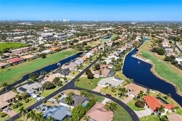 Aerial overview of property's location featuring a large body of water, nearby suburban area, and a local golf course