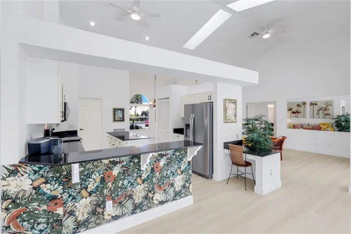 Kitchen featuring ceiling fan, stainless steel appliances, a skylight, a peninsula, and light wood-style flooring