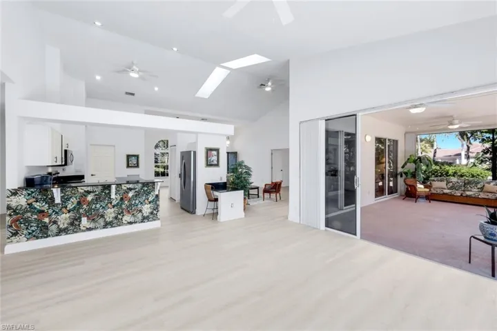 Living area featuring a ceiling fan, lofted ceiling, plenty of natural light, light wood-type flooring, and a skylight
