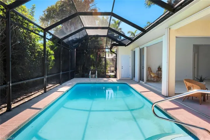 Outdoor pool with a patio area, glass enclosure, and a sunroom
