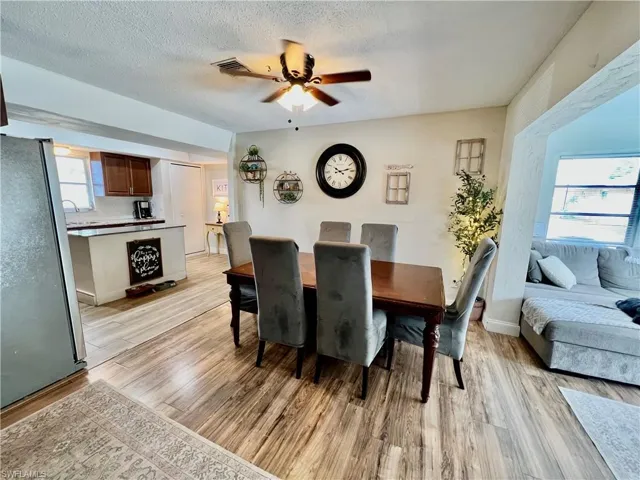 Dining room with ceiling fan, a textured ceiling, and light  wood-style floors. and a healthy amount of sunlight